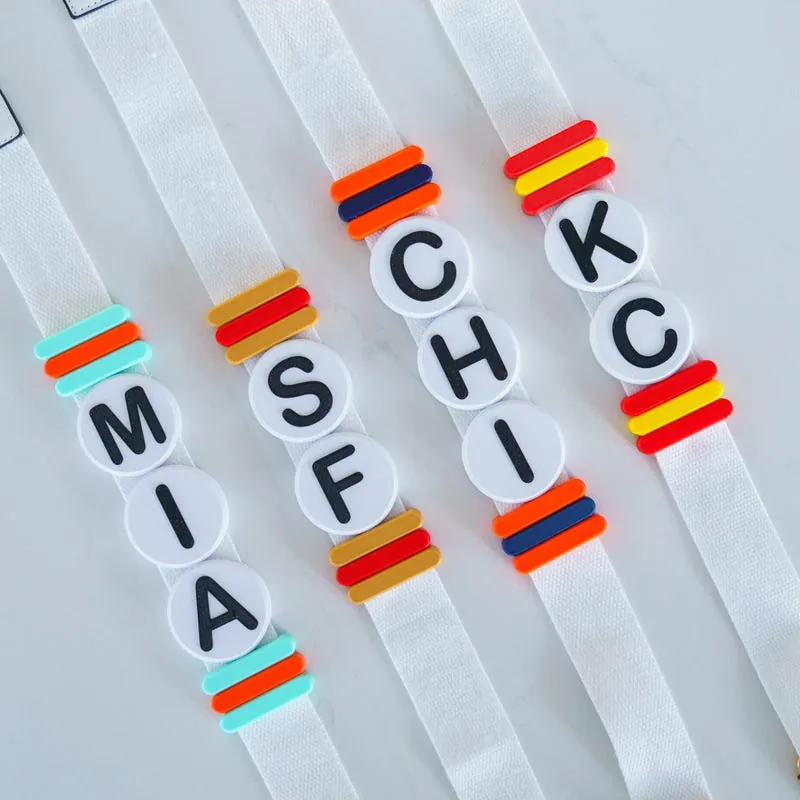 Lettered bead sliders on white bag straps