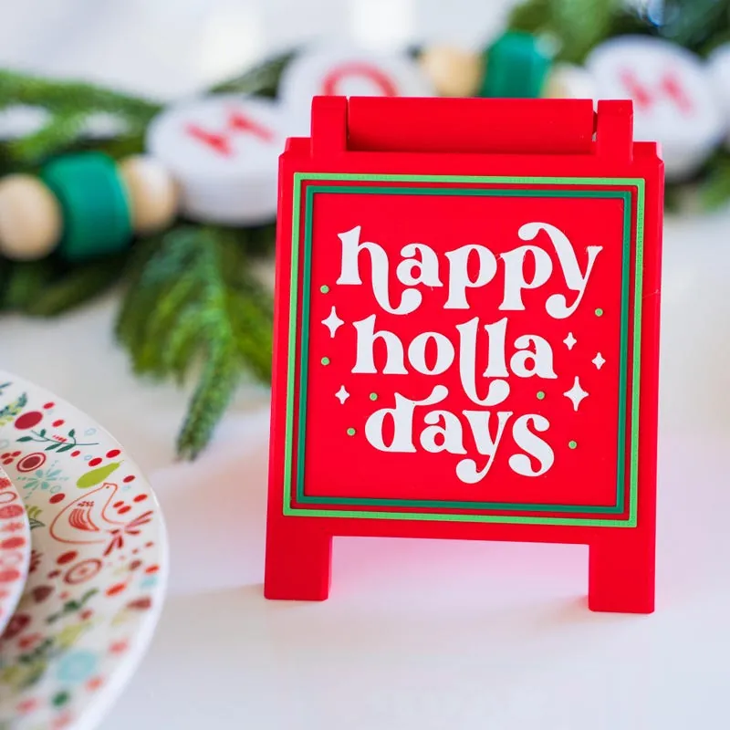 Red tray sign that reads happy holla days on a festive table